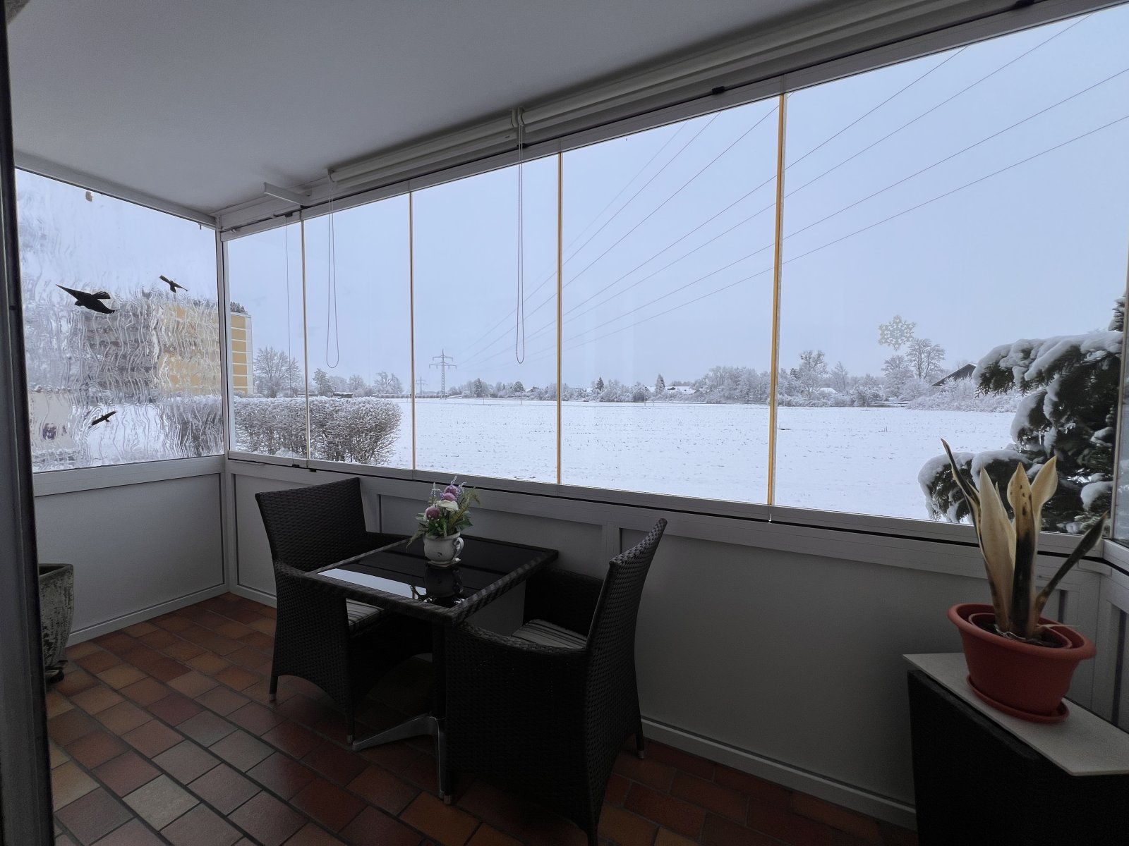 Gemütlicher Wintergarten mit Panoramablick auf verschneite Landschaft