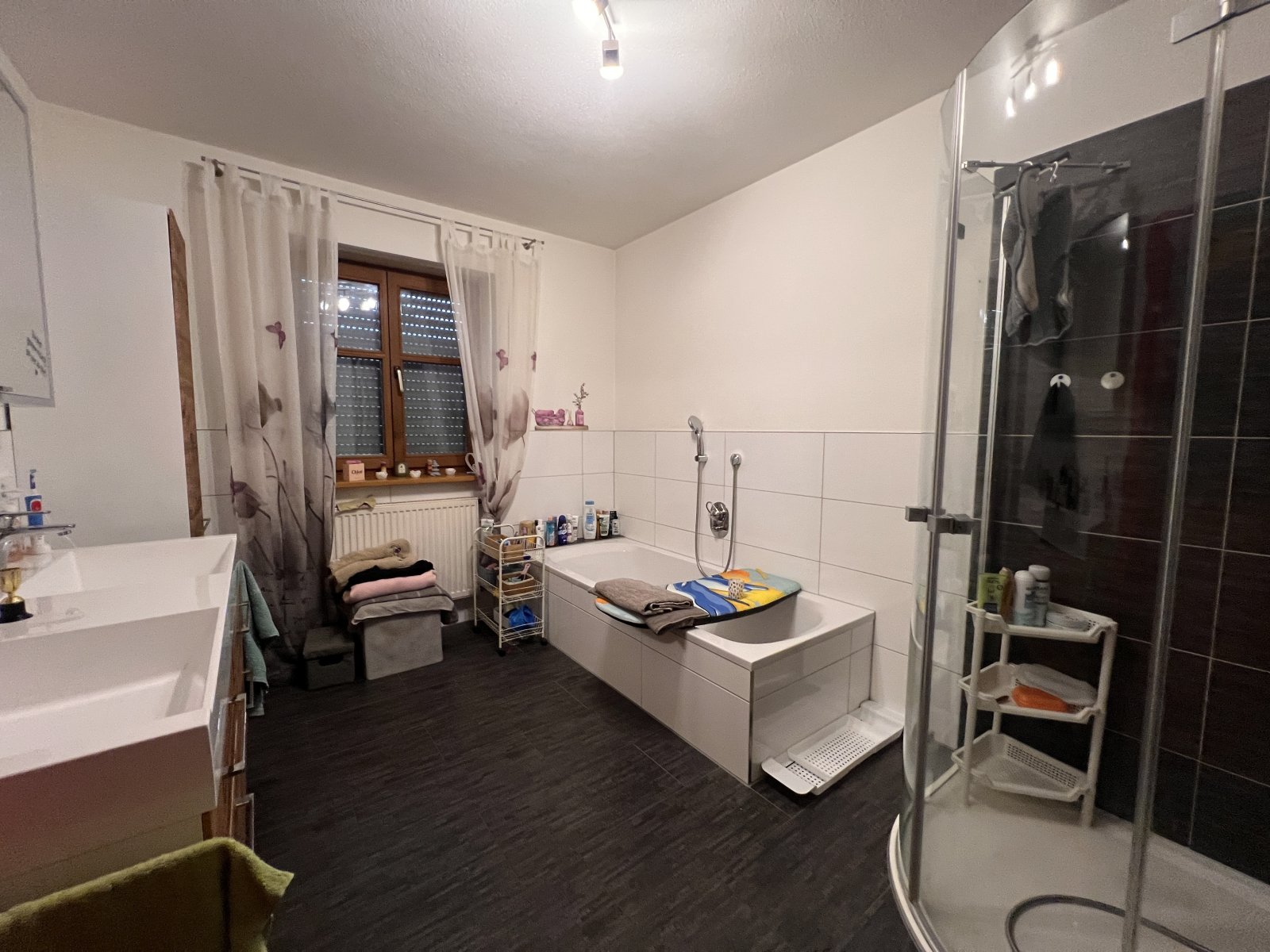 Geräumiges Badezimmer mit Badewanne, Dusche und praktischer Stauraumlösung