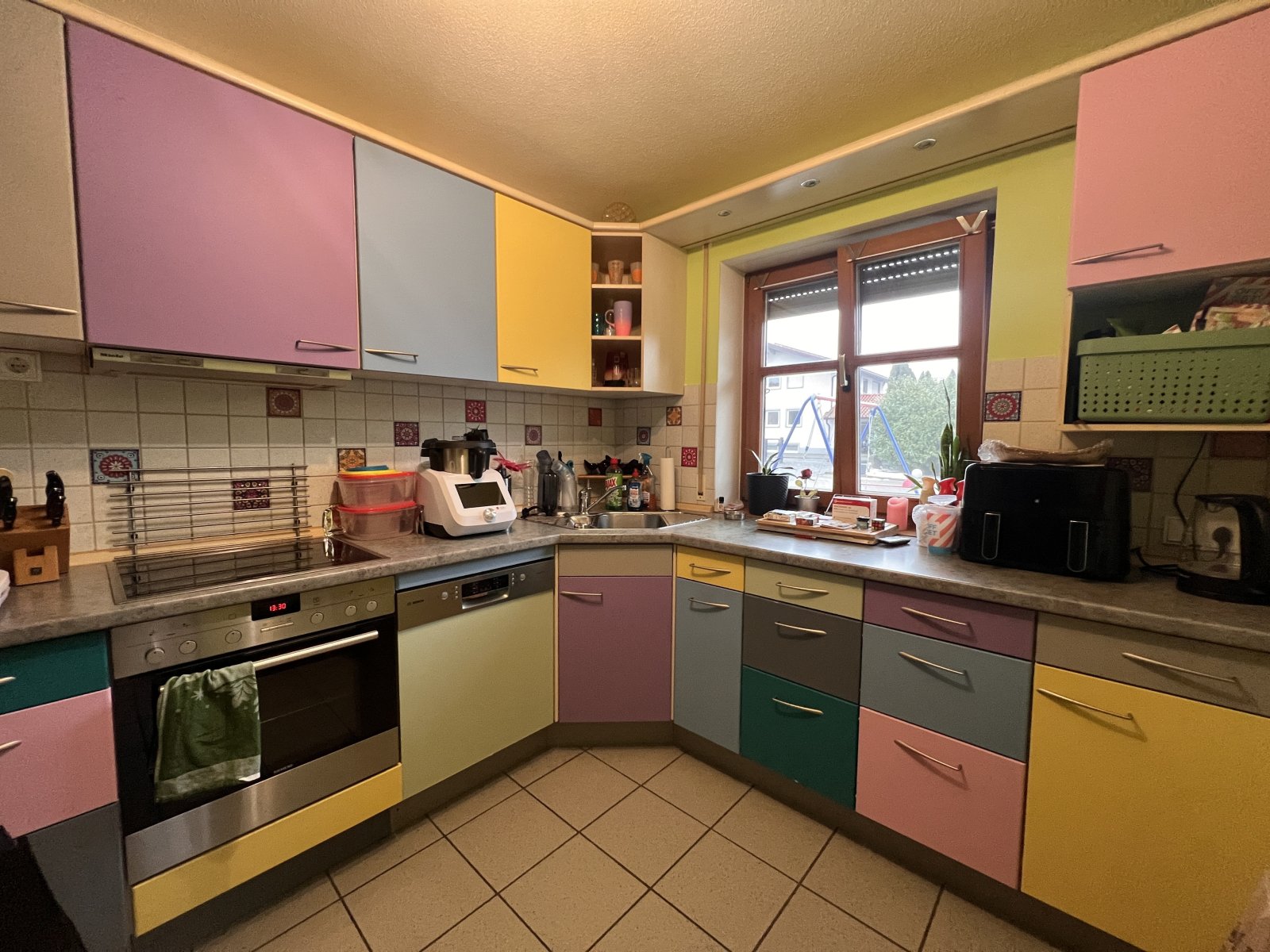 Helle, durchdachte Küche mit bunten, festverbauten Schränken und viel Stauraum