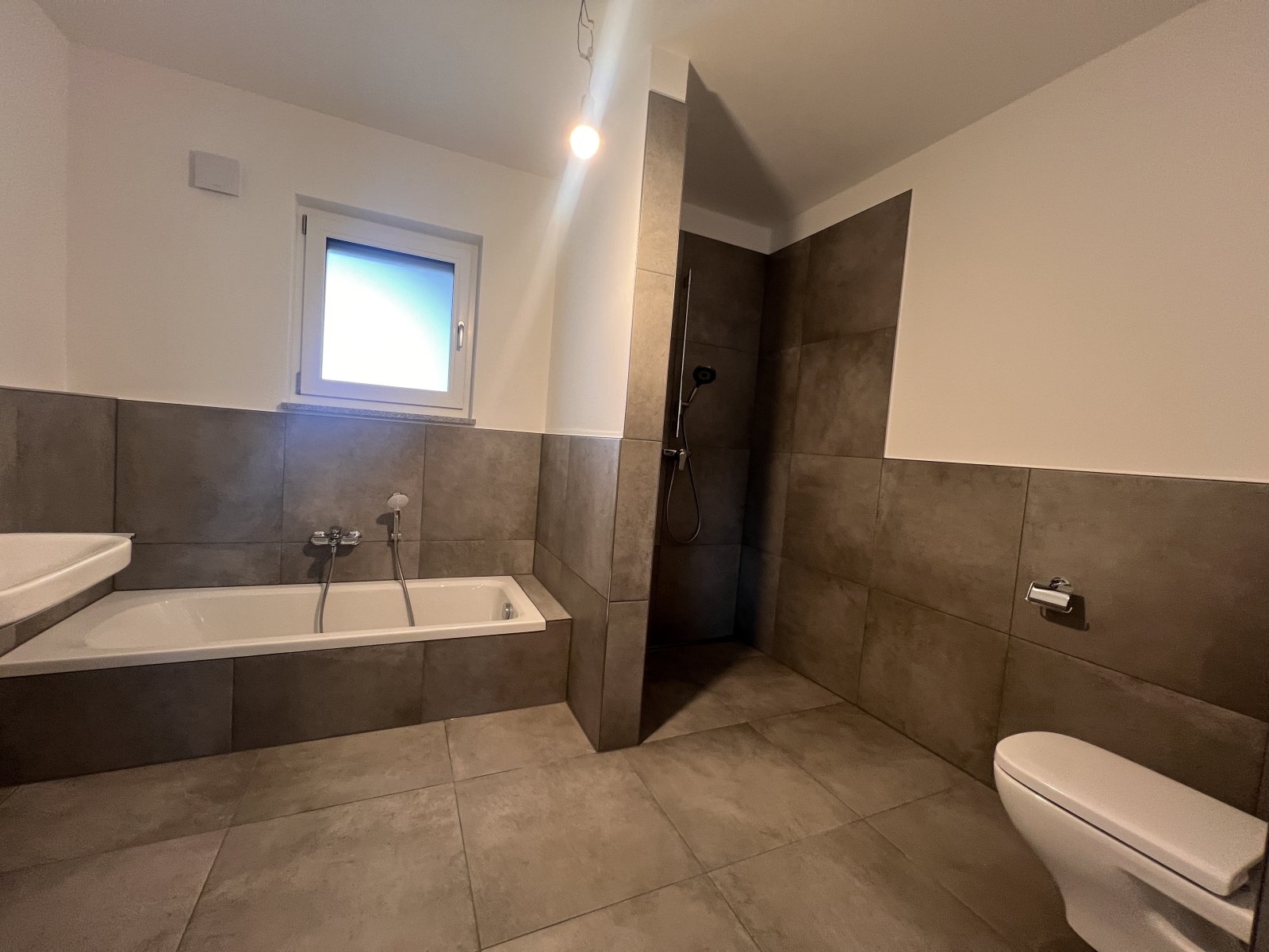 Modernes Wellness-Badezimmer mit bodengleicher Dusche und natürlichen Steinoptik-Fliesen